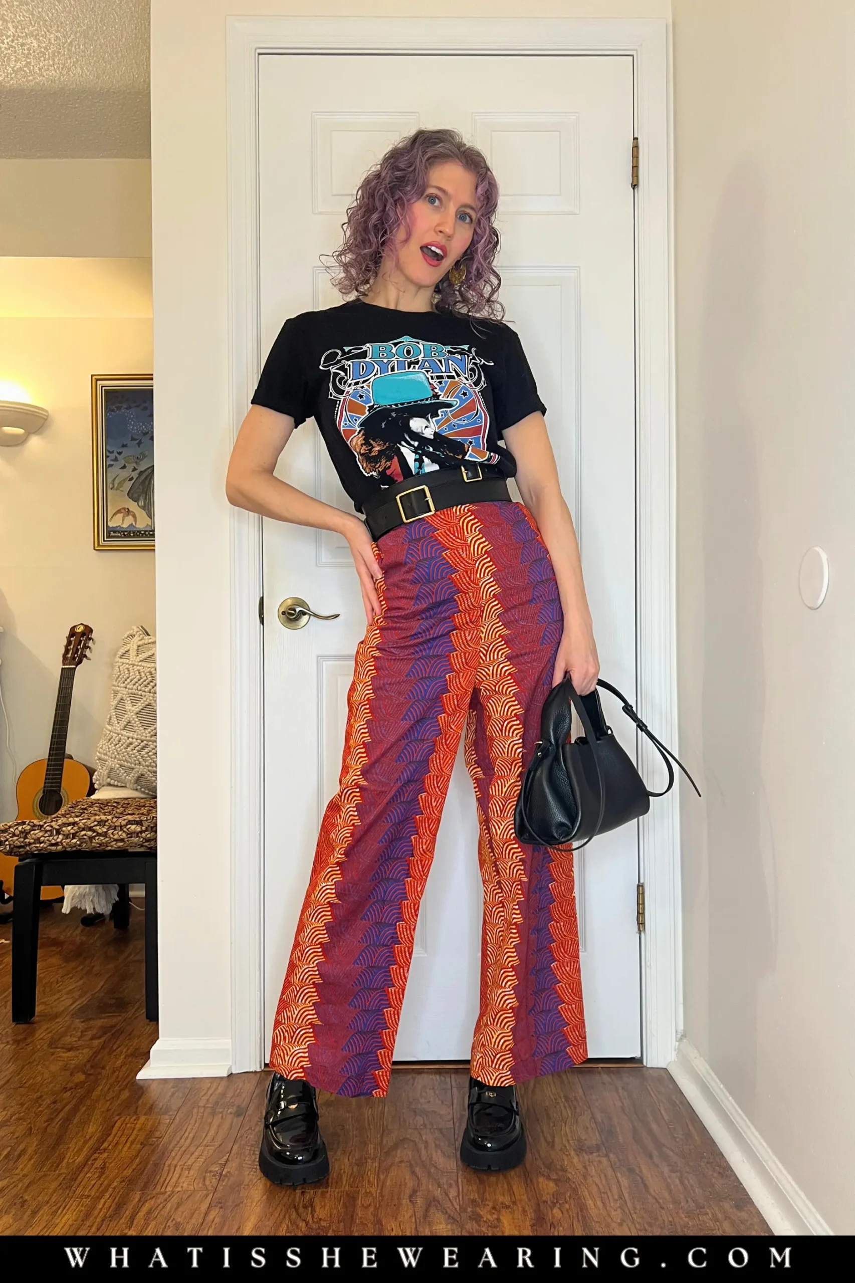 Woman showing how to style oversized band t-shirts cinched with a waist belt and paired with statement pants.