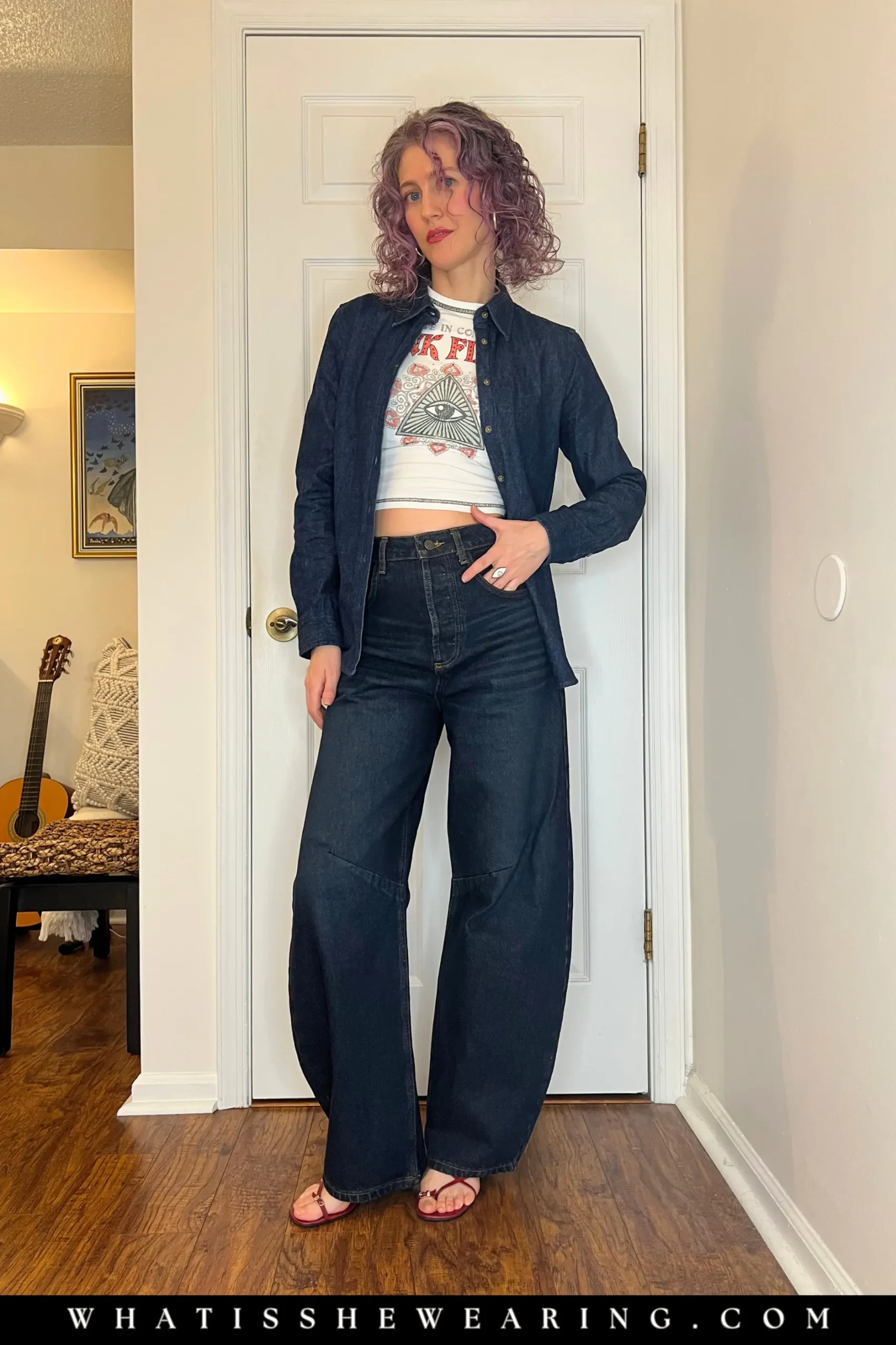 Woman modeling how to style band t-shirts in a double denim outfit with a fitted rock band tee and strappy sandals.