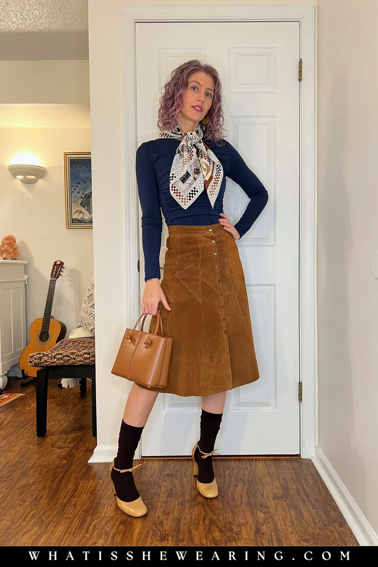 Chic Navy and Camel Weekend Outfit Woman in chic weekend navy blue top with camel suede skirt, silk scarf, and Mary Jane pumps—what to wear with navy blue for warm, vintage-inspired earthy elegance.