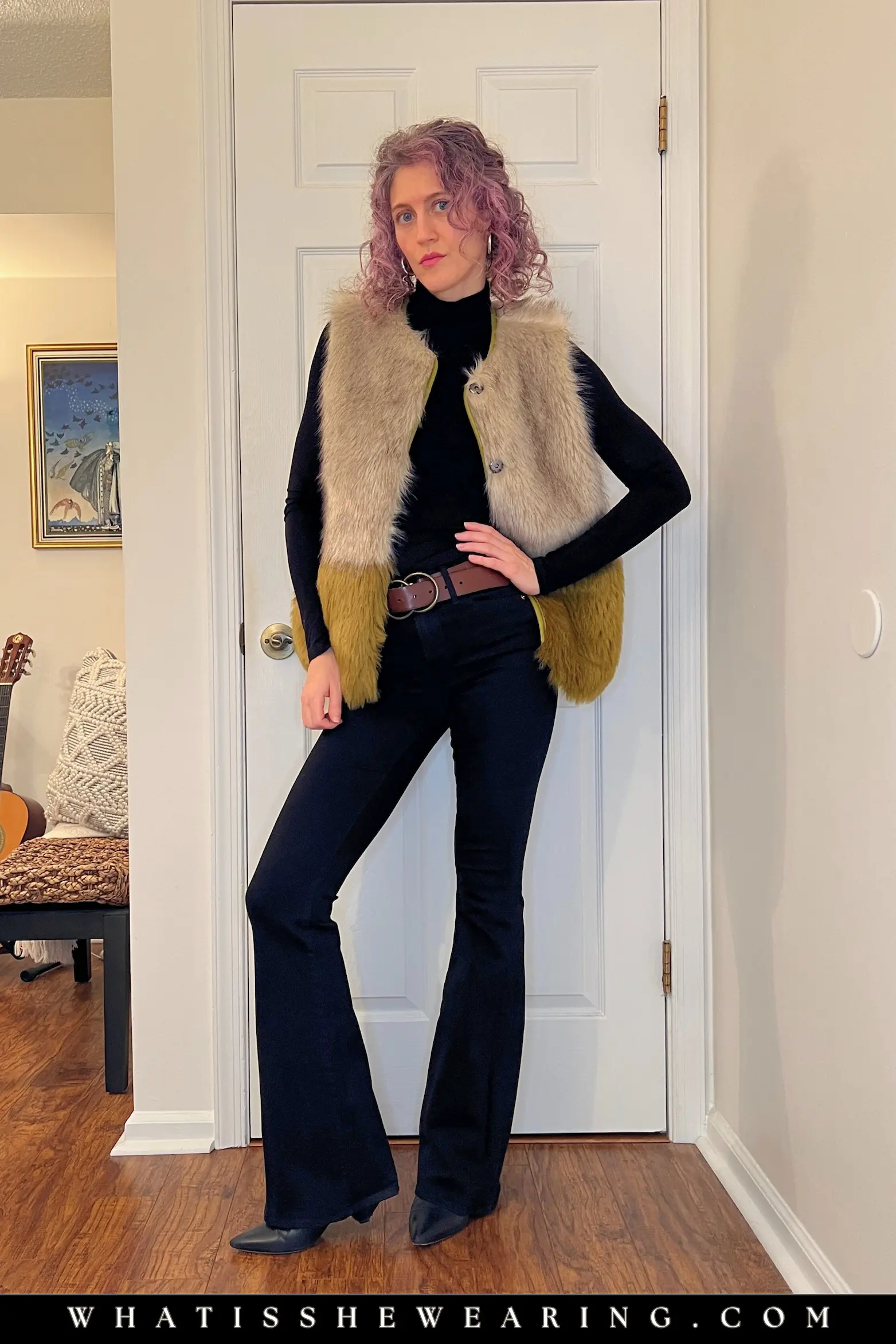 Tip 2: Dark Base with Faux Fur Vest for Chic Winter Outfits Woman in black turtleneck and black flare jeans with faux fur vest layered on top