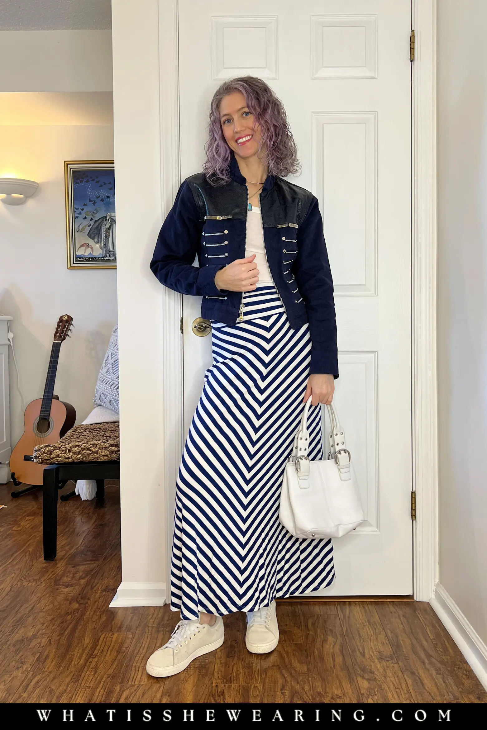 Maxi Skirt and Statement Jacket Outfit Idea Woman in a striped maxi skirt with a basic white top, denim statement jacket, white bucket bag, and ivory sneakers - elevated casual everyday outfit